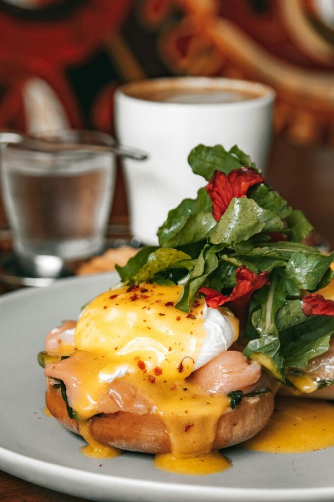 Savor a perfect brunch of eggs benedict with fresh greens and coffee.